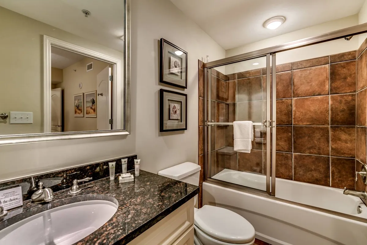A spa-like bathroom with a granite countertop, glass shower enclosure, and elegant framed artwork. The space is serene and inviting, ideal for relaxing soaks and self-care routines after a day of adventure.